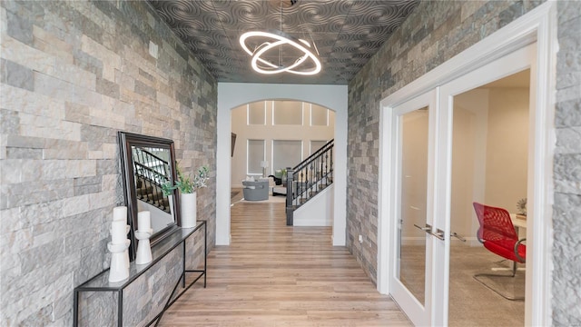 corridor with stairway, french doors, light wood finished floors, and a chandelier