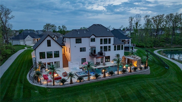 rear view of property with a lawn, an outdoor pool, a patio area, a balcony, and stairs