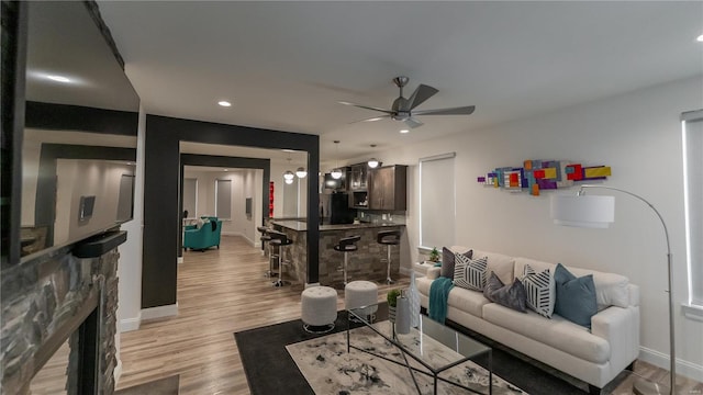 living room featuring a ceiling fan, baseboards, recessed lighting, and light wood-style floors