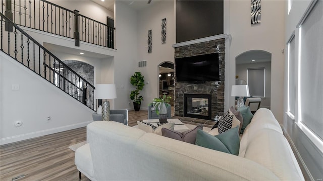 living room with baseboards, visible vents, wood finished floors, and a towering ceiling