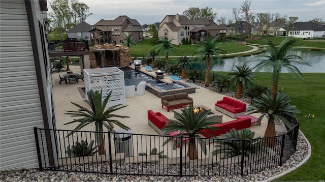 view of patio with a water view, fence, a residential view, and an outdoor living space with a fire pit