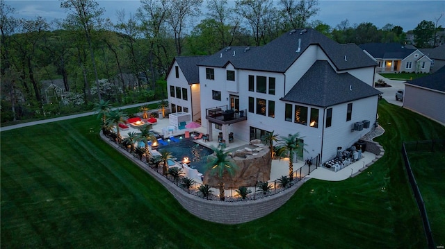 back of house featuring a lawn, a patio, and a shingled roof