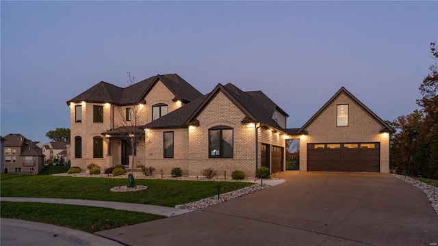 french country home featuring a garage, concrete driveway, a front lawn, and brick siding