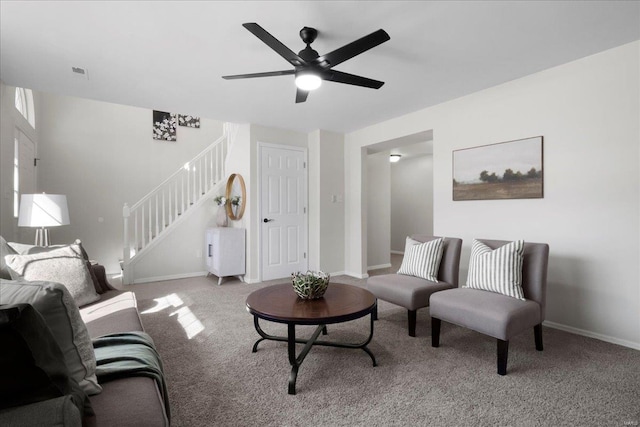 living area with carpet, visible vents, ceiling fan, baseboards, and stairs