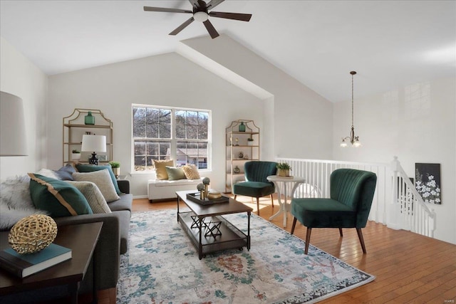 living room featuring lofted ceiling, ceiling fan with notable chandelier, and hardwood / wood-style flooring