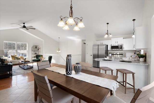 dining space featuring lofted ceiling, light tile patterned floors, and ceiling fan with notable chandelier