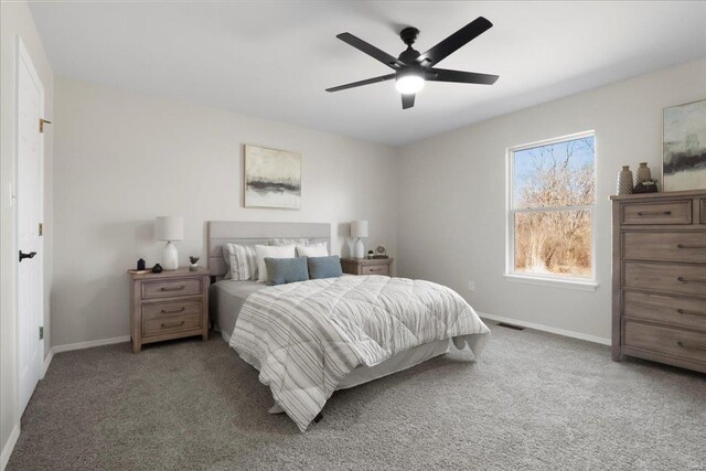 carpeted bedroom featuring a ceiling fan, visible vents, and baseboards