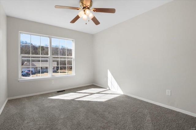 carpeted spare room with baseboards, visible vents, and ceiling fan