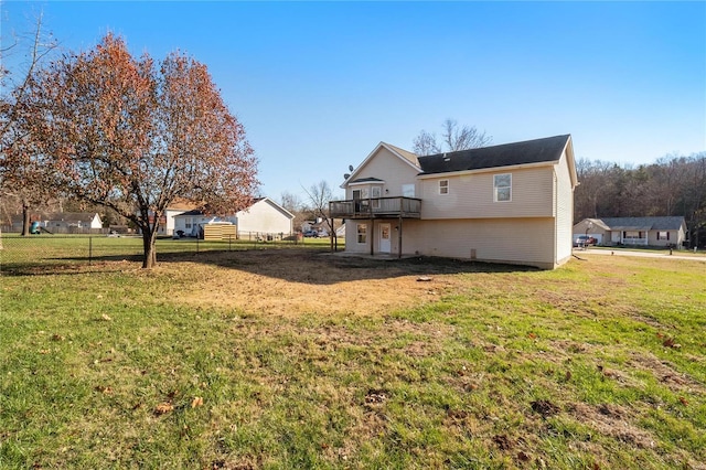 rear view of house with a deck, a yard, and fence