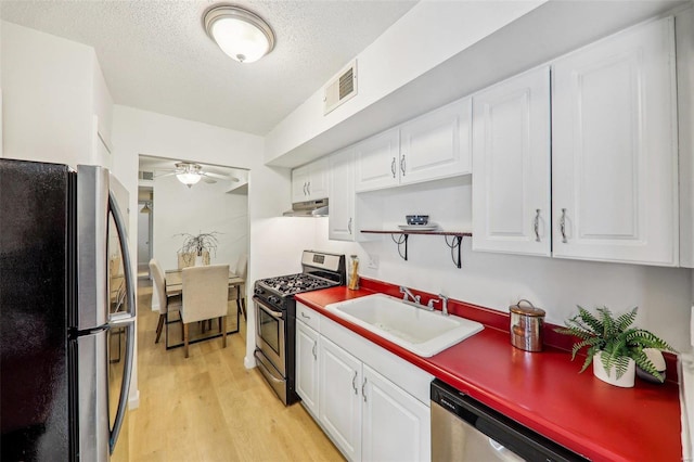 kitchen featuring sink, appliances with stainless steel finishes, white cabinetry, a textured ceiling, and light wood-type flooring