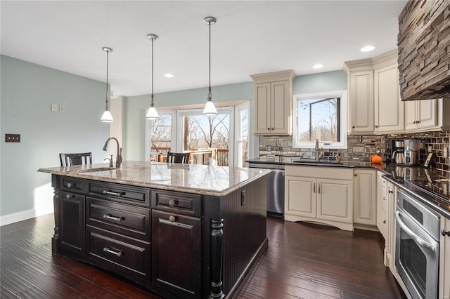 kitchen featuring stainless steel appliances, an island with sink, hanging light fixtures, and sink