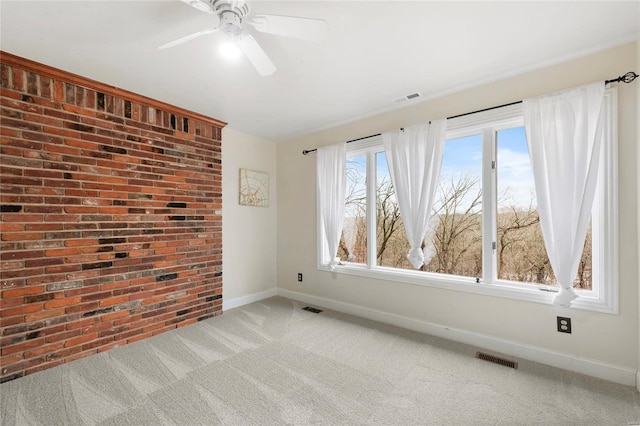 unfurnished room with ceiling fan, brick wall, and carpet floors