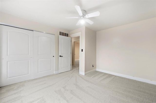 unfurnished bedroom featuring light carpet, ceiling fan, and a closet