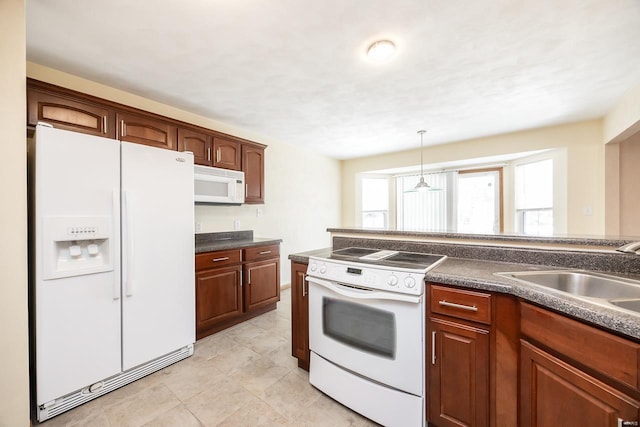 kitchen featuring dark countertops, hanging light fixtures, light tile patterned flooring, a sink, and white appliances