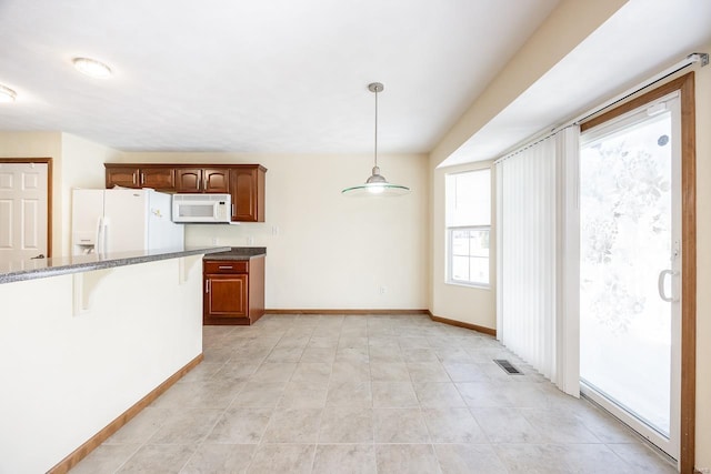 kitchen featuring a breakfast bar area, white appliances, visible vents, baseboards, and hanging light fixtures