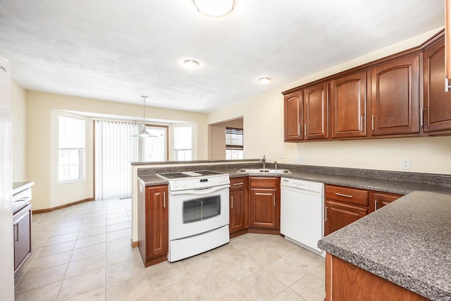 kitchen with a peninsula, white appliances, dark countertops, and a sink