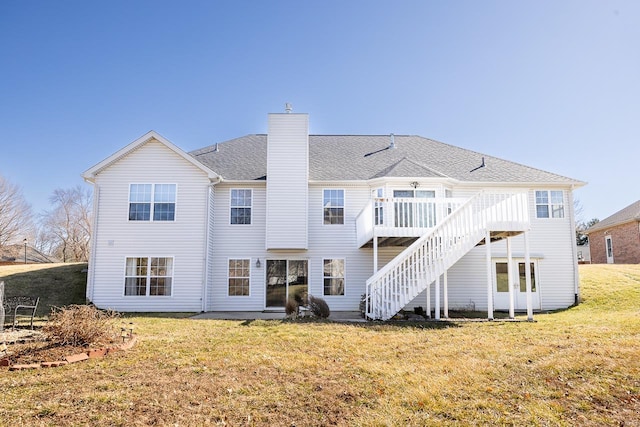 rear view of property with a shingled roof, a chimney, a lawn, and a wooden deck