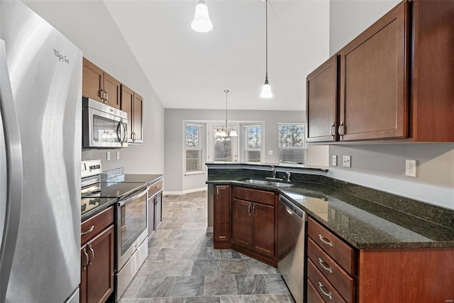 kitchen with appliances with stainless steel finishes, pendant lighting, lofted ceiling, sink, and dark stone countertops