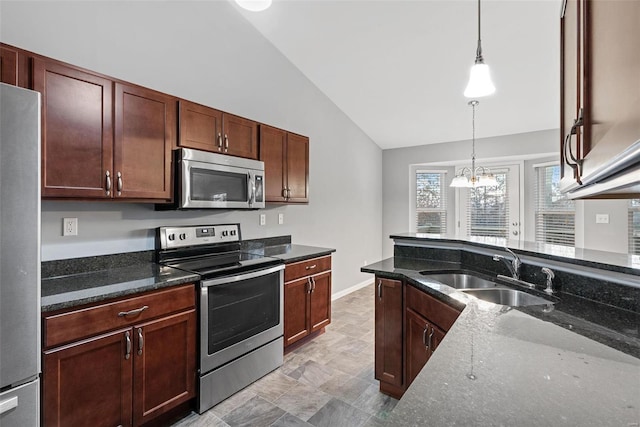 kitchen featuring sink, decorative light fixtures, vaulted ceiling, appliances with stainless steel finishes, and dark stone counters