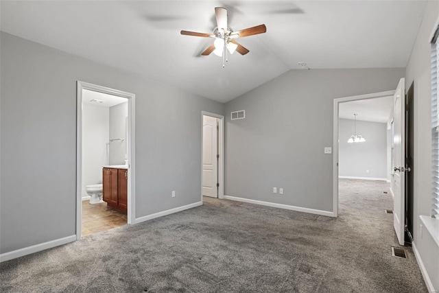 unfurnished bedroom featuring an inviting chandelier, light colored carpet, ensuite bathroom, and vaulted ceiling