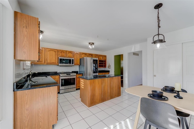 kitchen featuring light tile patterned flooring, tasteful backsplash, hanging light fixtures, a center island, and stainless steel appliances