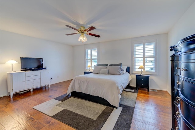 bedroom featuring ceiling fan, dark hardwood / wood-style floors, and multiple windows