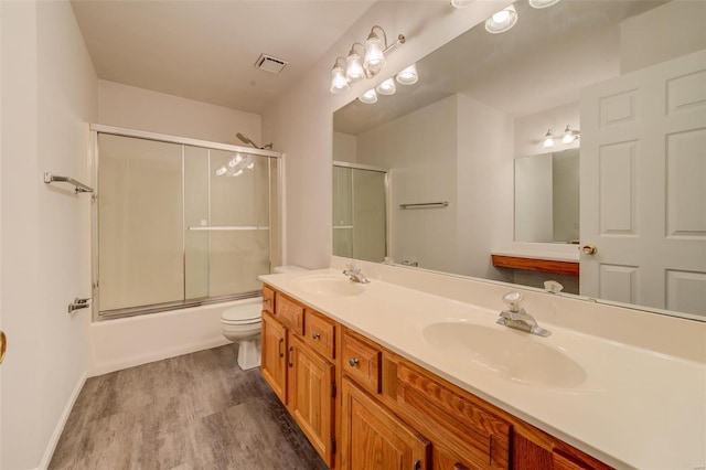 full bathroom with enclosed tub / shower combo, vanity, toilet, and hardwood / wood-style floors