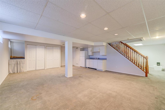 basement featuring white refrigerator, a paneled ceiling, and light carpet