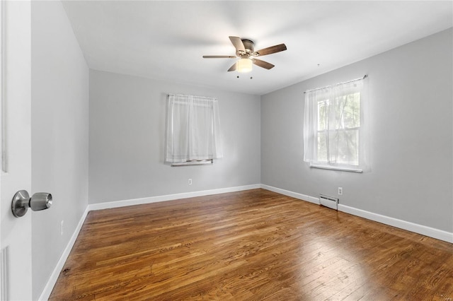 empty room with hardwood / wood-style flooring, ceiling fan, and a baseboard heating unit