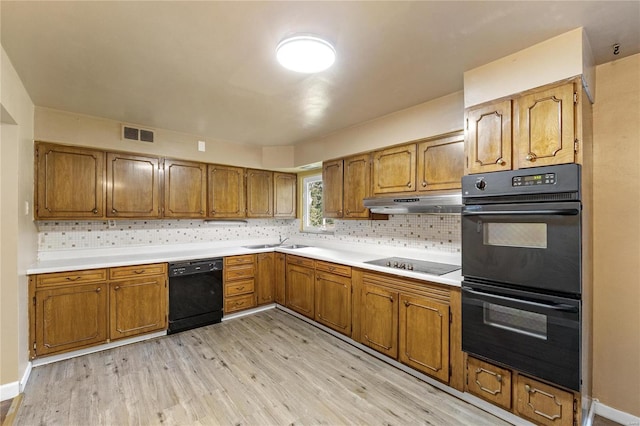 kitchen featuring sink, decorative backsplash, black appliances, and light wood-type flooring