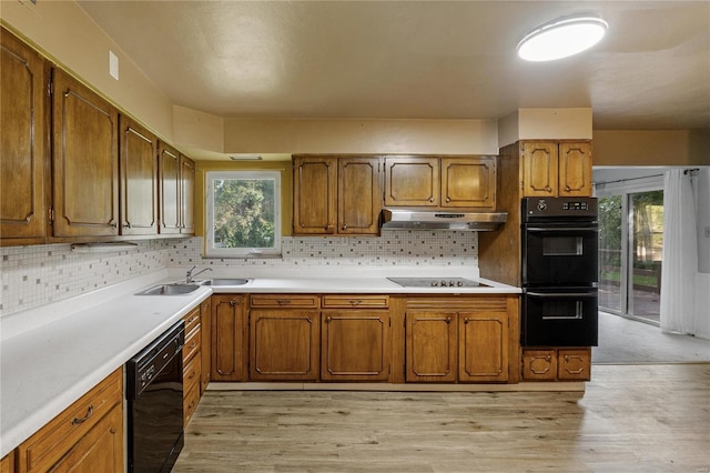 kitchen featuring sink, decorative backsplash, light hardwood / wood-style floors, and black appliances