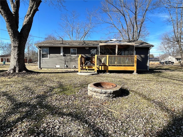 back of property featuring a wooden deck, a yard, and an outdoor fire pit