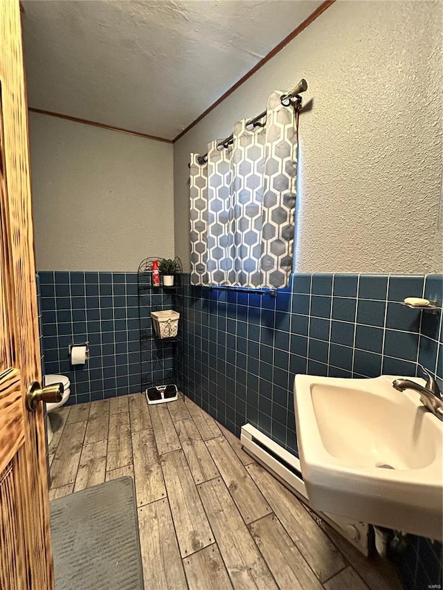 bathroom with crown molding, tile walls, wood-type flooring, a textured ceiling, and toilet