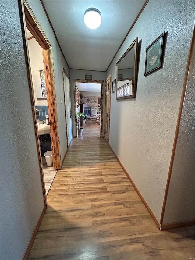 hallway with ornamental molding and light hardwood / wood-style floors