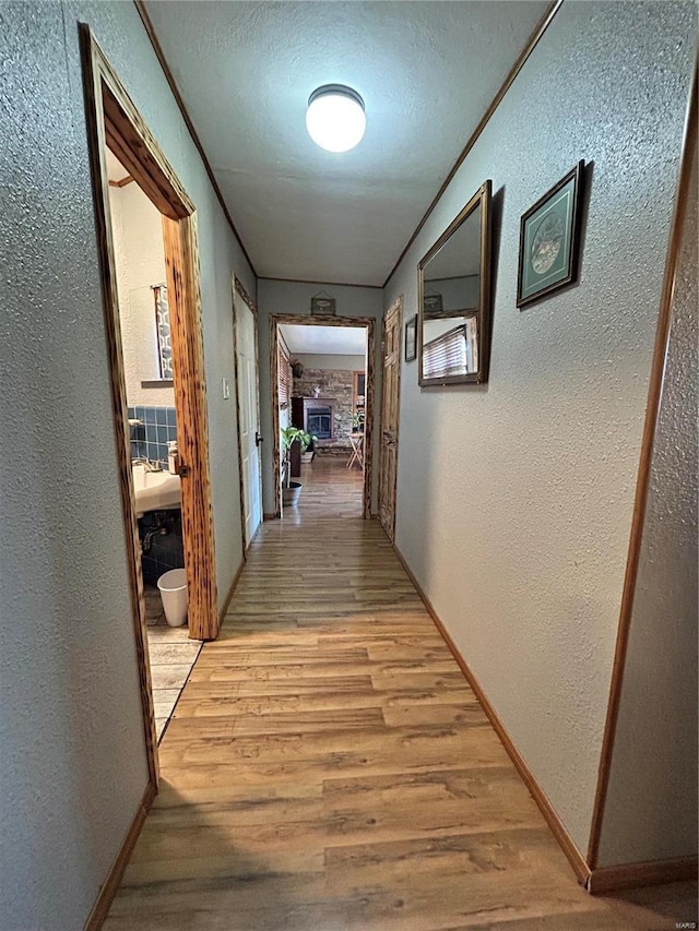 corridor featuring crown molding, light hardwood / wood-style flooring, and a textured ceiling