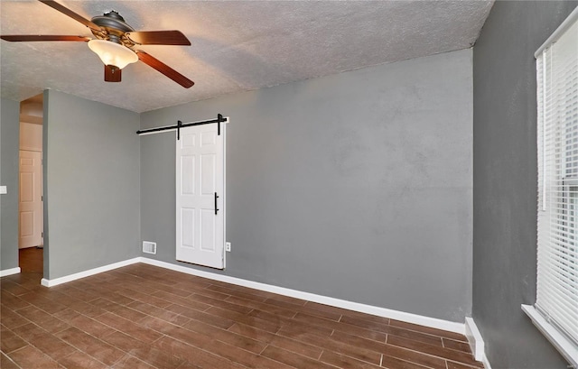 interior space featuring dark hardwood / wood-style floors, ceiling fan, a barn door, and a textured ceiling