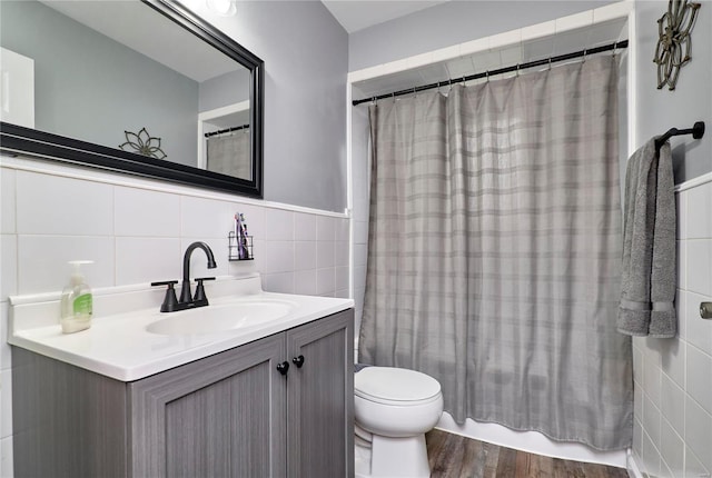 full bathroom with shower / tub combo with curtain, tile walls, hardwood / wood-style flooring, vanity, and toilet