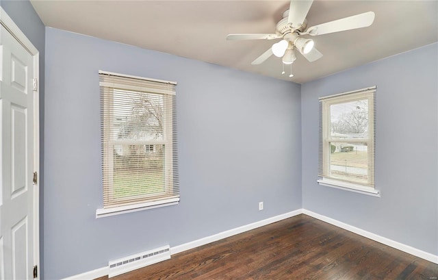 empty room featuring dark hardwood / wood-style flooring, ceiling fan, a healthy amount of sunlight, and baseboard heating