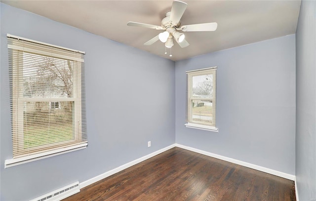 empty room featuring a baseboard heating unit, dark wood-type flooring, and ceiling fan