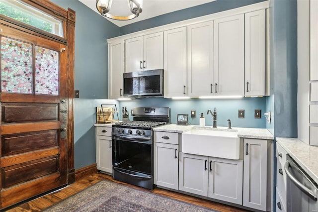 kitchen featuring sink, light stone counters, appliances with stainless steel finishes, dark hardwood / wood-style floors, and white cabinets