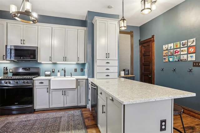 kitchen with appliances with stainless steel finishes, pendant lighting, sink, white cabinets, and dark wood-type flooring