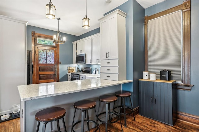 kitchen featuring white cabinetry, hanging light fixtures, dark hardwood / wood-style flooring, kitchen peninsula, and stainless steel appliances