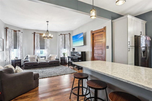 kitchen with a kitchen breakfast bar, stainless steel fridge, decorative light fixtures, and white cabinets