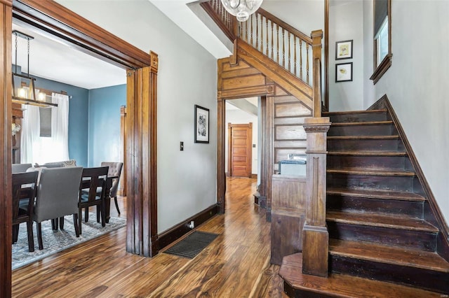 stairs with hardwood / wood-style floors and a notable chandelier