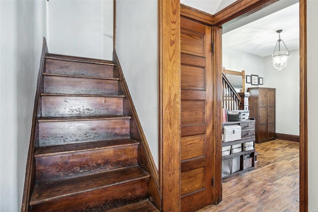 stairway featuring hardwood / wood-style floors and a notable chandelier