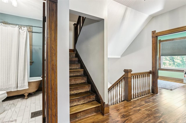 stairway with hardwood / wood-style flooring and lofted ceiling