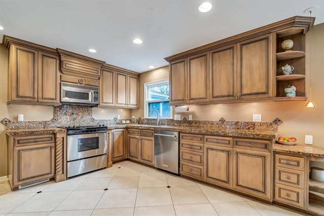 kitchen featuring sink, stone countertops, light tile patterned floors, appliances with stainless steel finishes, and backsplash