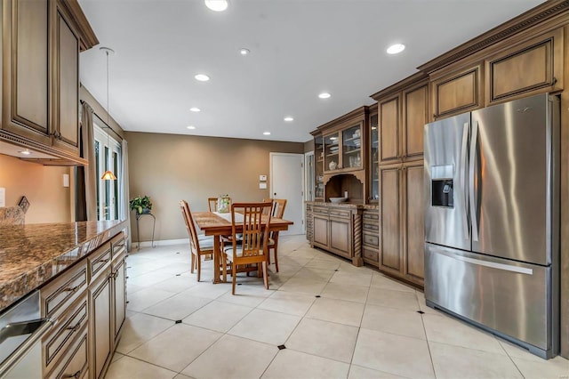 kitchen featuring dark stone countertops, stainless steel fridge, and light tile patterned floors