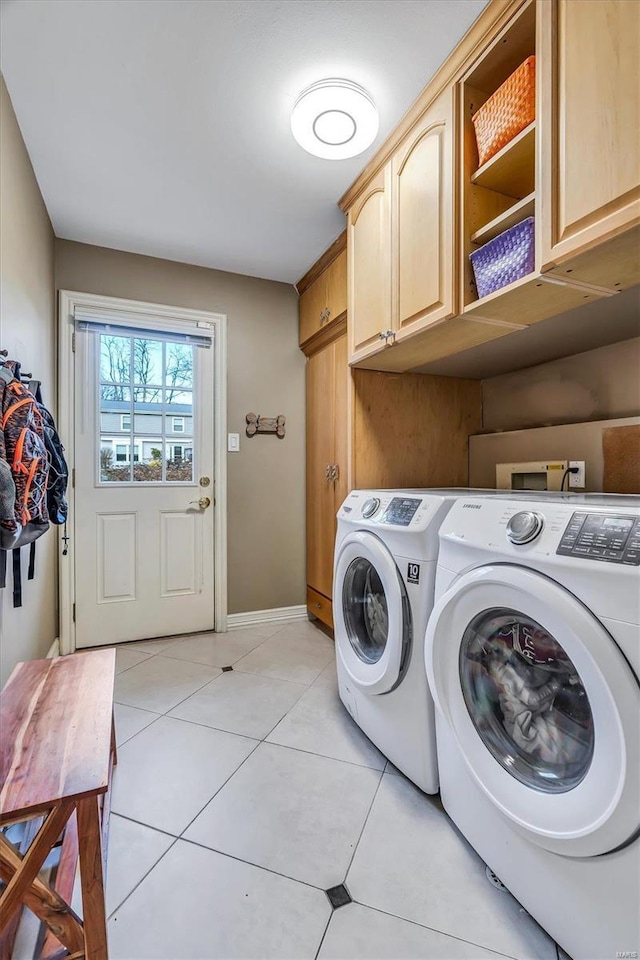 washroom featuring light tile patterned flooring, cabinets, and washer and dryer