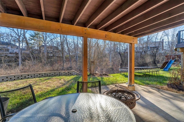 view of patio with a playground, a fire pit, and a trampoline